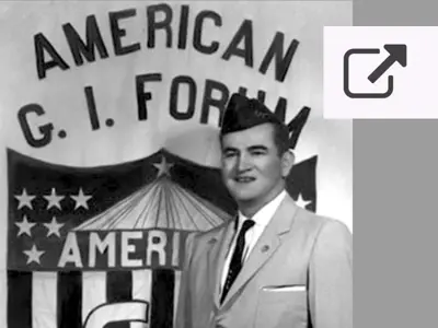 photo of a man in front of GI Forum banner