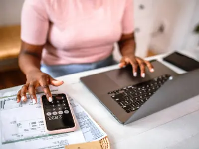 Woman Using Calculator and Laptop