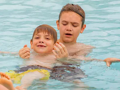 Boy teaching toddler to swim