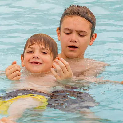 Boy teaching toddler to swim