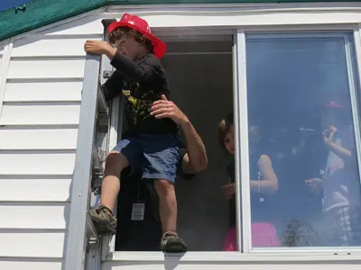 Boy practicing a fire escape out of a window