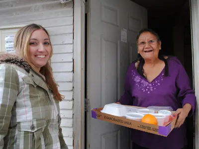 Young Woman bringing a meal to an elderly woman