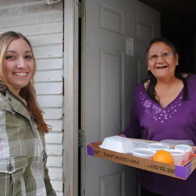 Young Woman bringing a meal to an elderly woman